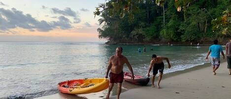 Une scène de plage avec des personnes qui se promènent et un kayak sur le sable.