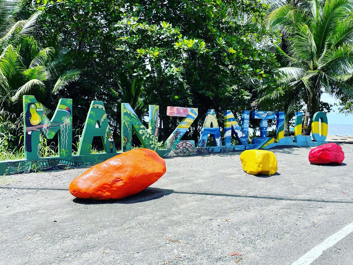 A road sign with the name "MANZANERO" and colorful letters.