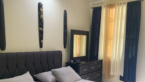 Un dormitorio con cama, mesita de noche, cómoda y espejo.