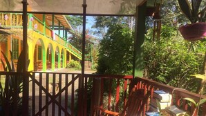 Un espacio al aire libre techado con barandilla de madera, una banca y una mesa con periódicos.