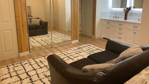 A modern living room with a large mirror, a sofa, and a wooden wardrobe.