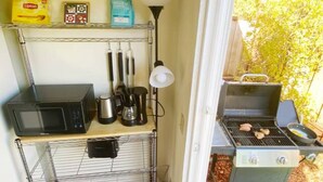 Una kitchenette compacta equipada con microondas, cafetera y parrilla.