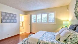 Un dormitorio con cama, ventana y puerta que da a otra habitación.