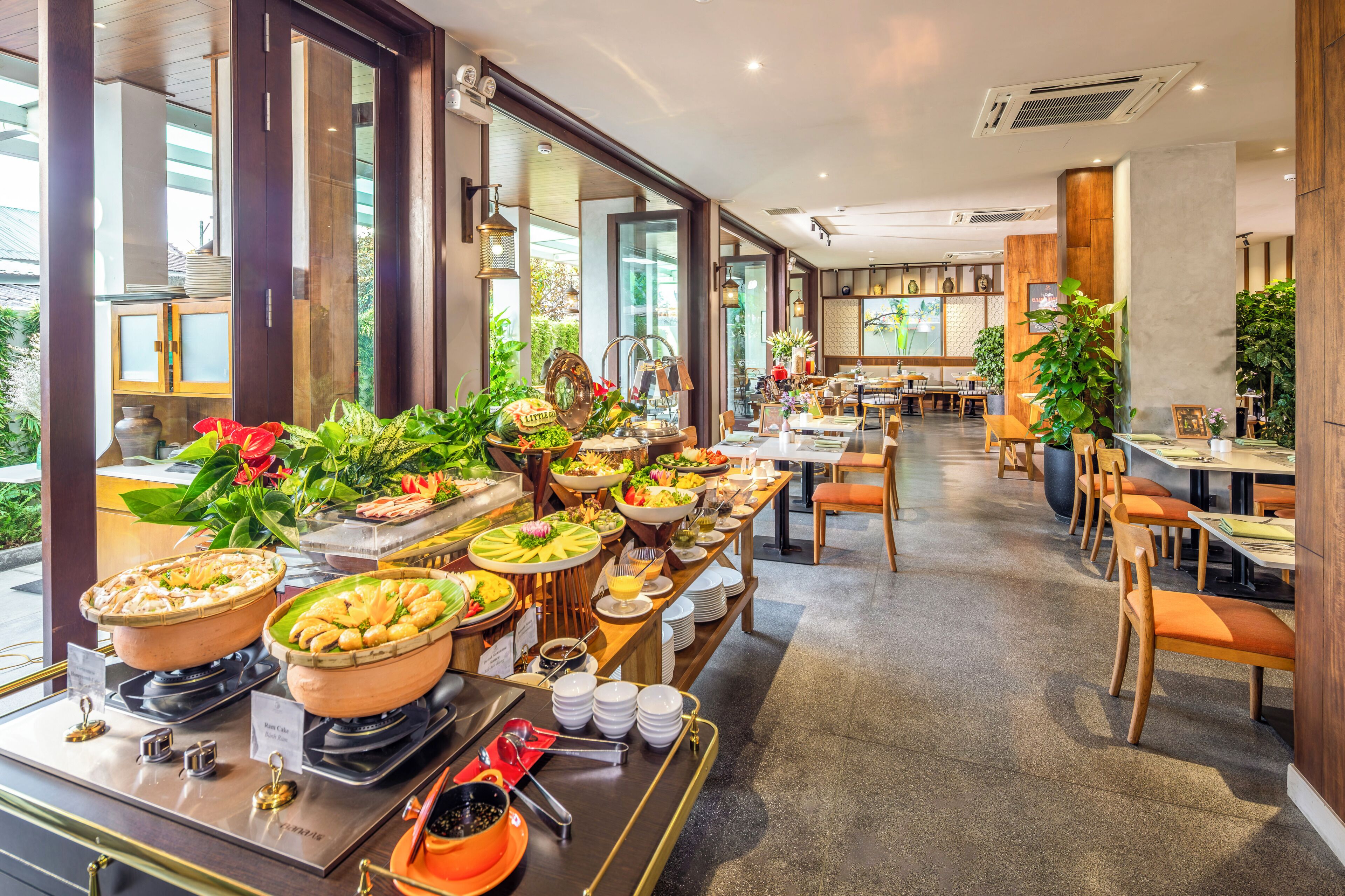 Buffet-alue, jossa on tarjolla monenlaista ruokaa, sekä ruokailualue, jossa on pöytiä ja tuoleja.