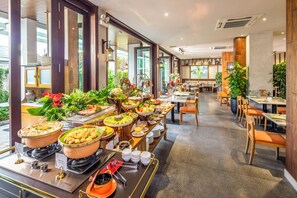Un espace buffet proposant divers plats et une zone de restauration avec des tables et des chaises.