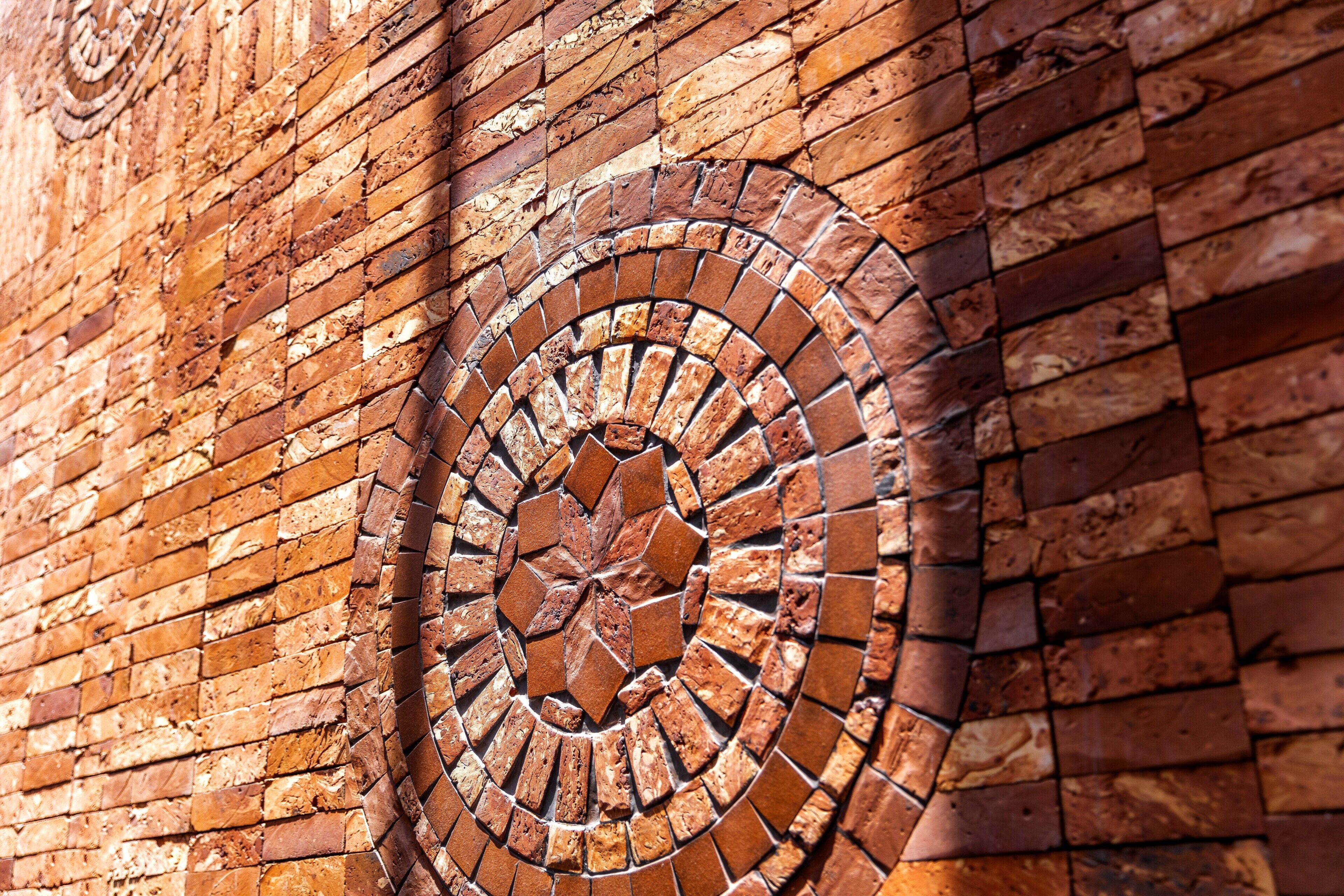 A close-up of a brick wall with a circular mosaic pattern.