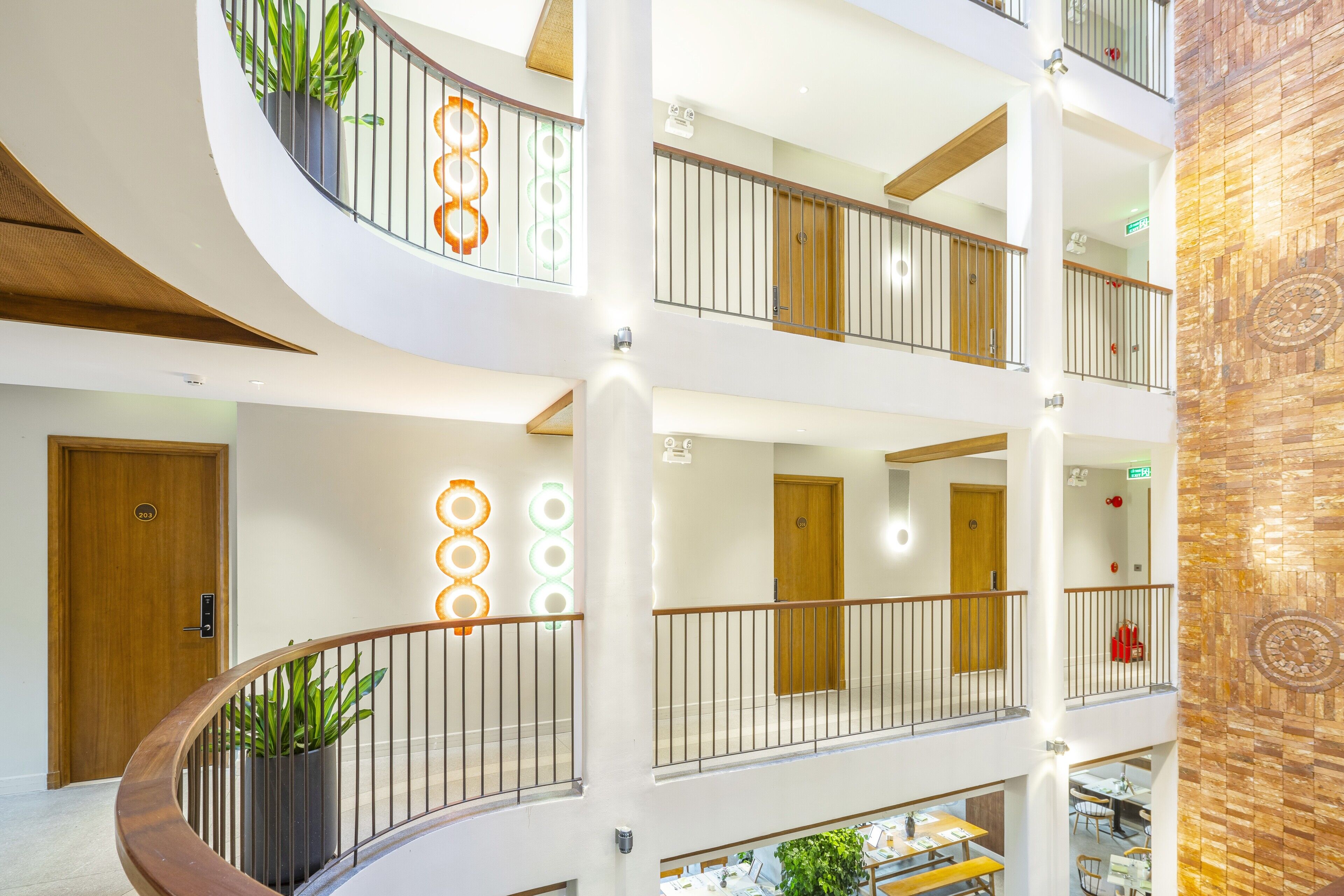 Ein Hotel mit mehreren Etagen, einem zentralen Atrium, Balkonen und einem Speisebereich.