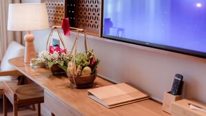 Ein Holztisch mit Lampe, Obstkorb, Fernbedienung und Notizbuch.