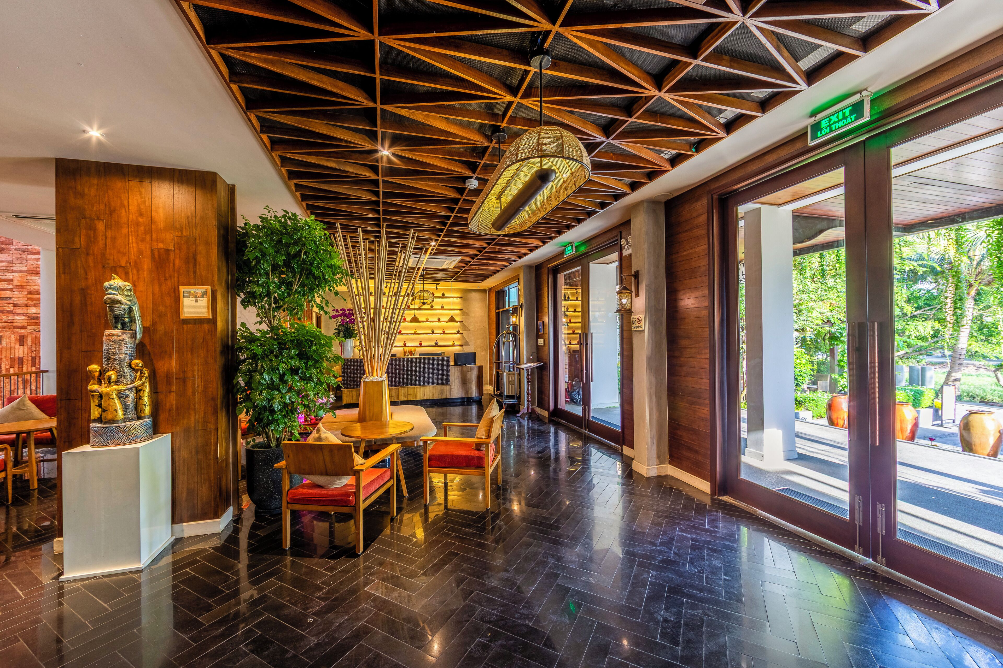 A hotel lobby with a modern design, featuring a wooden ceiling, a reception desk, and a seating area with chairs and a table.