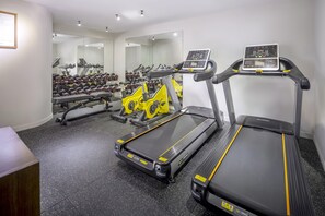 Un gimnasio con cintas de correr, una bicicleta estática y una prensa de pesas.
