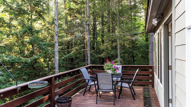 A wooden deck with a table and chairs, surrounded by a forest. - Spacious Home near Diana's Baths! (Conway)