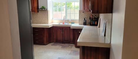 A kitchen with wooden cabinets, a tiled backsplash, a window, and a sink.