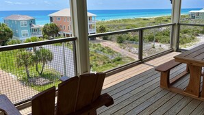 A wooden deck with chairs and a table, overlooking a beach and houses. - The Sea Life (Port St. Joe)