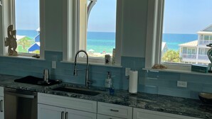 A kitchen with a view of the ocean, a sink, and a countertop with a coffee maker. - The Sea Life (Port St. Joe)