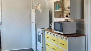 Een keuken met witte kastjes, een magnetron en een fornuis.