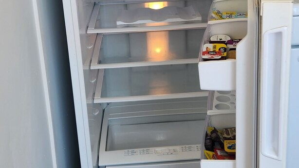 Een witte koelkast met meerdere planken en een waterdispenser.