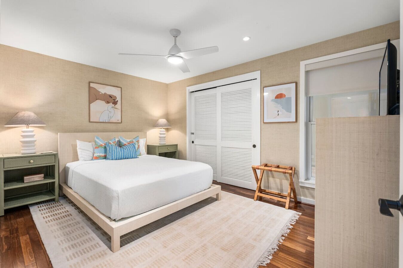 A bedroom with a bed, nightstands, a ceiling fan, a window, and a door.