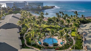 Een resort met een zwembad, omringd door palmbomen, een strand en uitzicht op de oceaan.