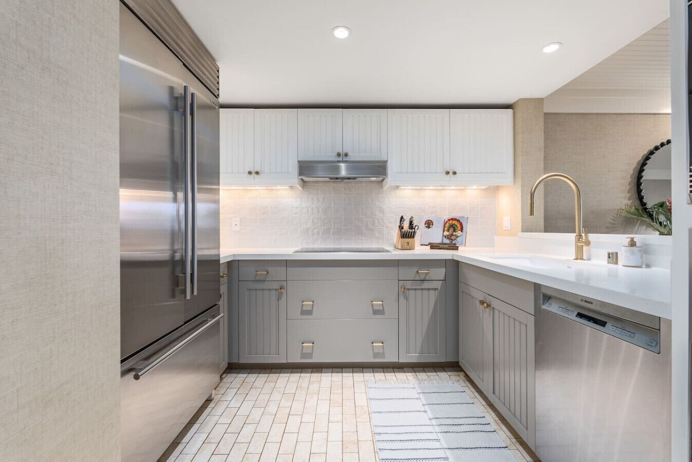 A modern kitchen with grey cabinets, stainless steel appliances, and a white countertop.