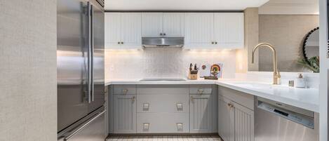 A modern kitchen with grey cabinets, stainless steel appliances, and a white countertop.