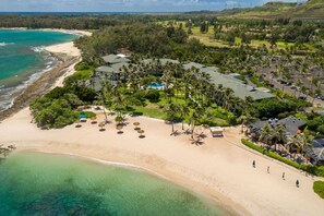 An aerial view of a resort with a beachfront, palm trees, and a golf course in the background. - Ohana Turtle Bay Ocean Villa - Beach/Luxury Resort/Pool & Jacuzzi (Kahuku)