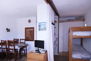 Cozy retreat with a wooden bunk bed, desk, and dining table, perfect for travelers seeking a functional space.