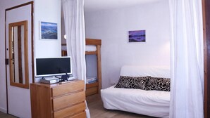 A bedroom with a bunk bed, a TV on a wooden dresser, and two framed pictures on the wall. - LARGE STUDIO 6 PEOPLE RESORT CENTER (LES ORRES 1650)