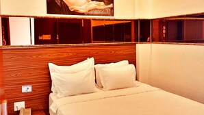 A bedroom with a wooden headboard, a bed with white linens, a nightstand with a phone, and a red rug.