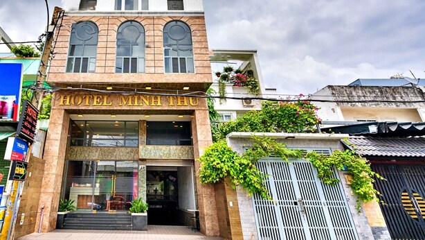 A hotel with a prominent tower, large arched windows, and a sign reading "HOTEL MINH THU".