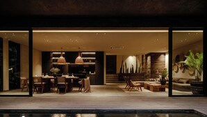 A modern interior with a dining area, kitchen, and living space, featuring a pool and large windows.