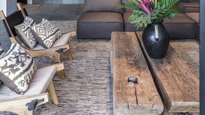 A modern living room with a stone wall, a cactus display, and a wooden coffee table with a vase.
