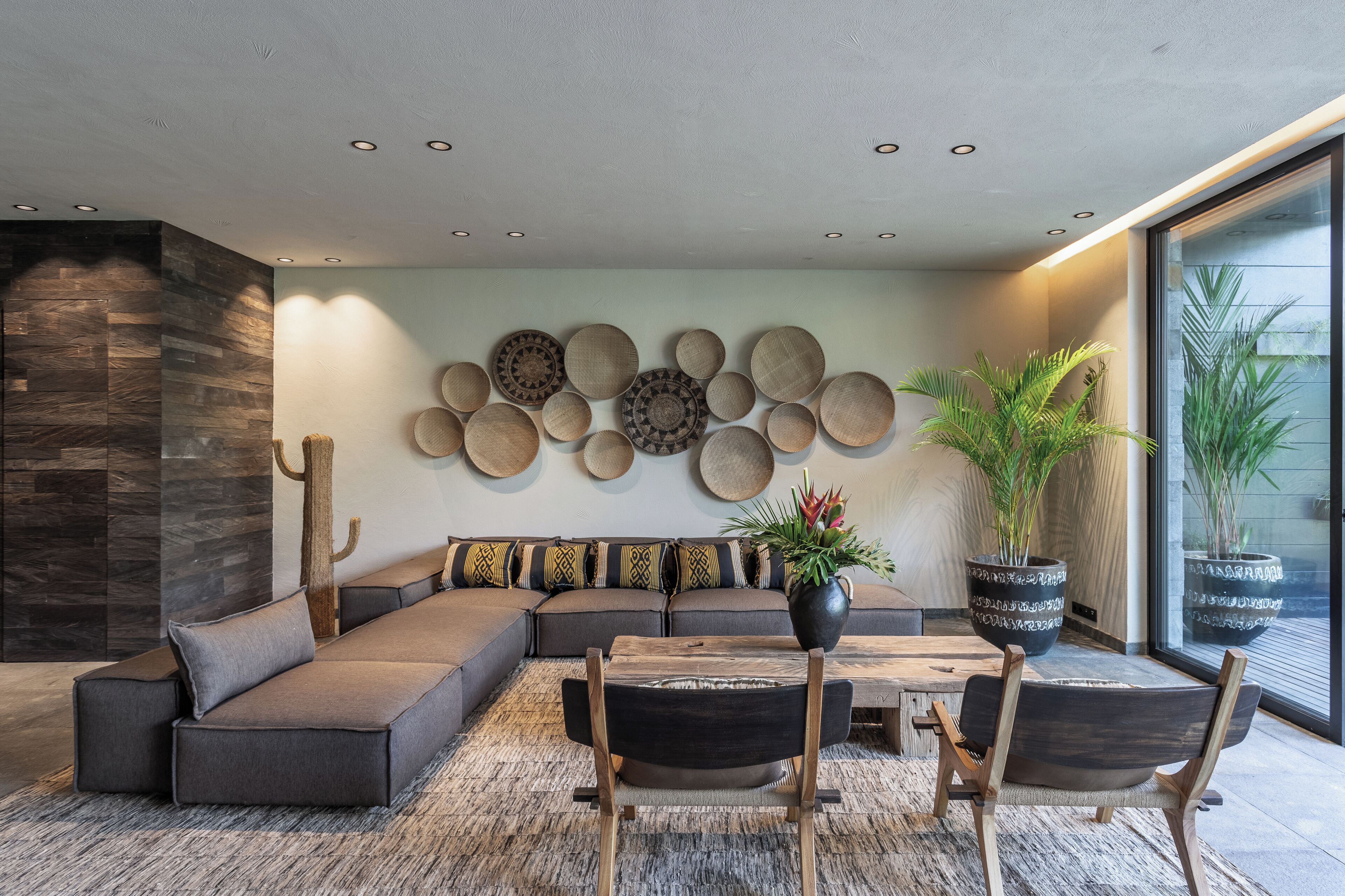Ein modernes Wohnzimmer mit einem Ecksofa, einem Holztisch und einer großen Topfpflanze.