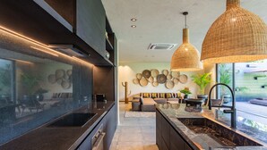 A modern kitchen with dark cabinetry, a marble island, and pendant lighting.