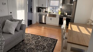 Una cucina compatta con mobili bianchi, lavastoviglie in acciaio inossidabile e forno integrato.