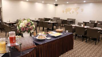 Un salón de conferencias con una larga mesa dispuesta para una reunión, equipado con sillas, un mapa mundial en la pared y un centro de mesa floral.