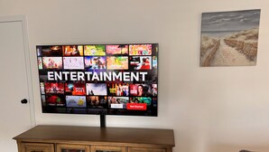 Un téléviseur à écran plat fixé au mur, qui affiche différentes options de divertissement.