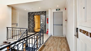 A hotel hallway with a marble wall, a fire extinguisher, and a door labeled "LOI THOAT EXIT". - HANZ Minh Thu Hotel Tan Binh (Ho Chi Minh City)