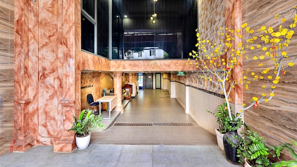 A hotel lobby with marble walls, a reception desk, a seating area, and potted plants. - HANZ Minh Thu Hotel Tan Binh (Ho Chi Minh City)