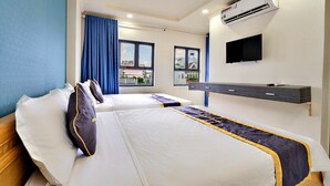 A hotel room with two beds, a TV, an air conditioning unit, and a window with a view of buildings. - HANZ Minh Thu Hotel Tan Binh (Ho Chi Minh City)