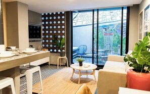 A modern living room with a dining area, a large window with a cityscape view, and a decorative wall with circular patterns. - Espectacular depto con terrazas en Condesa (Ciudad de México)