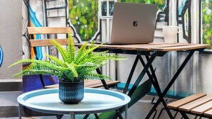 A laptop on a table with a potted plant, a white mug, and a wooden bench. - Espectacular depto con terrazas en Condesa (Ciudad de México)