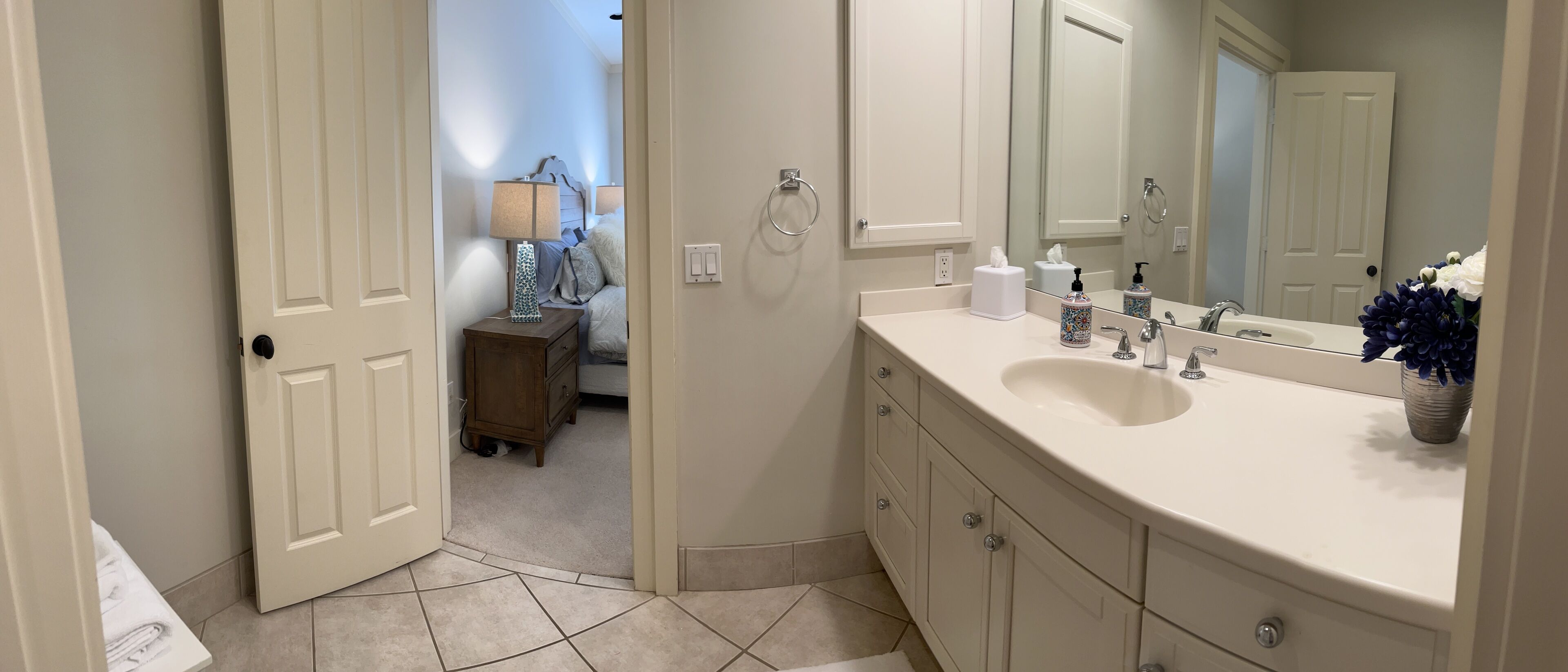 Une salle de bain avec un lavabo blanc, un miroir et une petite table de chevet avec une lampe.