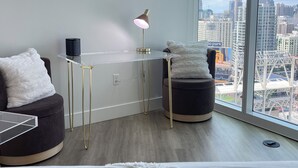 Habitación de hotel moderna con un ventanal grande, un escritorio, una silla, una cama y vistas a la ciudad.