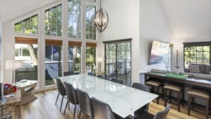 Una habitación amplia con ventanas grandes, una mesa de comedor, sillas, un sofá y un candelabro.