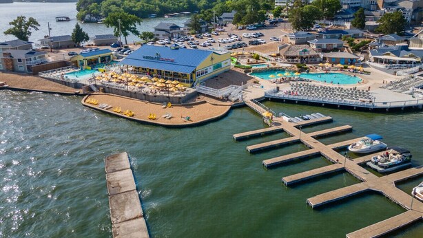 Un hotel frente al lago con varias piscinas, un muelle y vistas panorámicas.