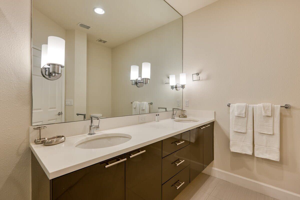 Une salle de bain moderne avec un grand miroir, deux lavabos et un porte-serviettes.