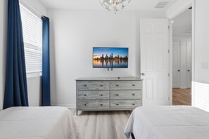 Ein Schlafzimmer mit zwei Betten, einer Kommode, einem Stadtbild und einer Tür zu einem anderen Raum.