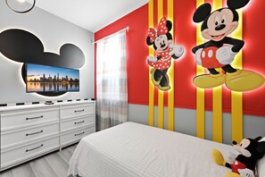 A bedroom with a bed, a dresser, a television, and Mickey Mouse decorations. - Stunning Retreat, Private Pool, Perfect Location (Kissimmee)