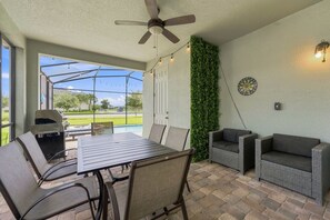 An outdoor patio with a table and chairs, a ceiling fan, a grill, and a dartboard. - Stunning Retreat, Private Pool, Perfect Location (Kissimmee)