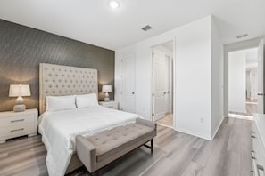 A bedroom with a bed, bedside tables, a bench, and a wardrobe.